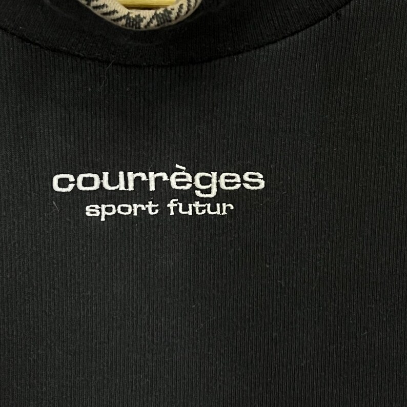 May include: Black ribbed knit top with the white embroidered text "courr&egrave;ges sport futur". The top has a crew neck and a close-up view of the brand's logo. The fabric appears to be a soft, comfortable material.