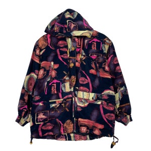 May include: A hooded jacket with a colorful abstract pattern. The jacket features a dark navy blue base with a mix of pink, orange, and yellow shapes. It has gold-colored buttons and drawstrings, and two front pockets.