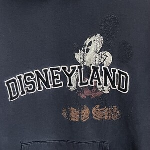Puede incluir: Una sudadera gris oscura con un gr&aacute;fico de Mickey Mouse de estilo vintage y el texto "DISNEYLAND" impreso en la parte delantera.