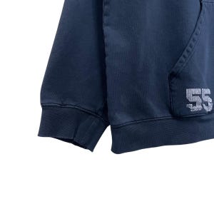 Puede incluir: Una sudadera con capucha azul oscuro con un n&uacute;mero "55" bordado en blanco en el lado derecho.