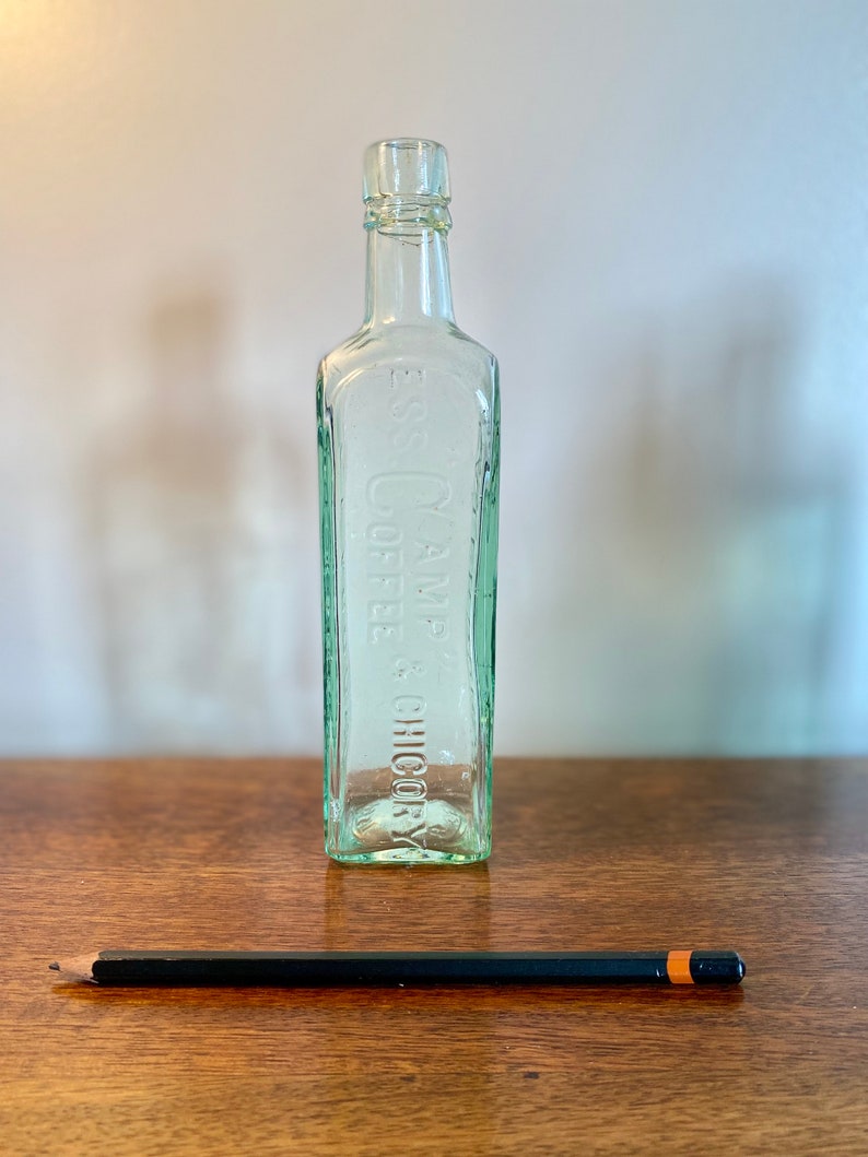K&ouml;nnte beinhalten: Eine klare Glasflasche mit strukturierter Oberfl&auml;che. Die Flasche ist mit dem Text "E.S. & C.Y. COFFEE & CHICORY" gepr&auml;gt.