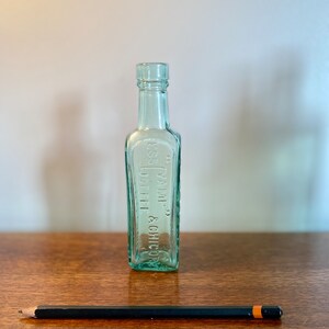 K&ouml;nnte beinhalten: Eine klare Glasflasche mit strukturierter Oberfl&auml;che. Die Flasche ist mit "YAMP. COFFEE & CHICORY" beschriftet.