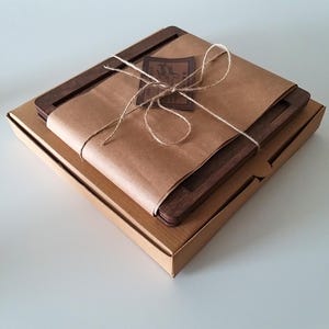 May include: A set of four wooden coasters wrapped in brown paper and tied with twine. The coasters are packaged in a brown cardboard box.