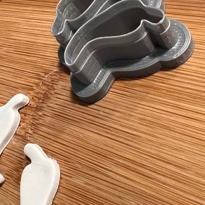 May include: A set of three gray plastic cookie cutters shaped like a chili pepper. The cutters are stacked on top of each other.