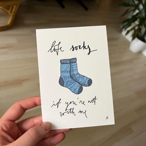 Könnte beinhalten: Eine weiße Karte mit gezeichneten blauen und weißen Socken mit Muster. Auf der Karte steht "love socks if you're not with me".