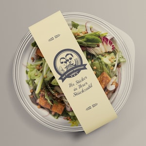 Könnte beinhalten: Ein weißer To-Go-Behälter mit einem durchsichtigen Deckel, gefüllt mit einem Salat. Der Salat enthält Salat, Linsen, rote Zwiebeln und Tofu. Ein gelber Aufkleber mit einem Logo und dem Text "The Sticker Brothers" ist am Behälter befestigt. Der Aufkleber sagt auch "Ihr Sticker in Ihrer Stückzahl".