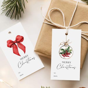 May include: Two white gift tags with "Merry Christmas" script. One tag features a red bow, the other a Christmas ornament with holly and berries. A wrapped gift with twine and pine needles complete the festive scene.