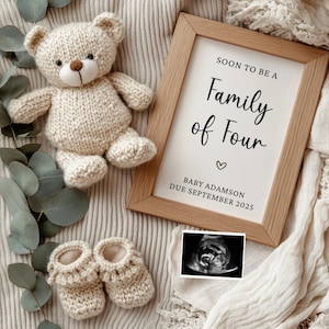 Puede incluir: Un cartel enmarcado con el texto "Soon to be a Family of Four" y las palabras "Baby Adamson Due September 2023". El cartel está rodeado de una manta de punto, un osito de peluche de punto y un par de zapatitos de punto. También hay una imagen de ultrasonido en blanco y negro.