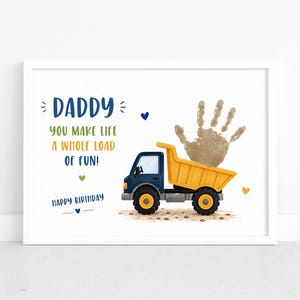 May include: A framed print featuring a yellow dump truck with a brown handprint in the bed. The text reads: DADDY YOU MAKE LIFE A WHOLE LOAD OF FUN! HAPPY BIRTHDAY. The design includes small blue, green, and yellow hearts on a white background.