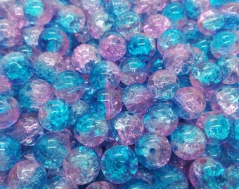 May include: A collection of clear, round beads in shades of blue and pink. The beads have a cracked, textured appearance, and are scattered across the image. These beads are suitable for jewelry making and crafts.
