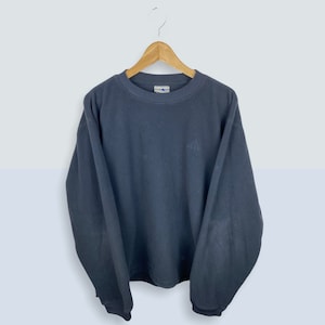 May include: A dark blue long-sleeved sweatshirt with a small logo on the front.