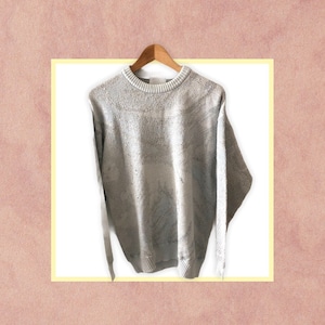 May include: A grey knitted jumper with a textured pattern. The jumper has a crew neck and long sleeves.