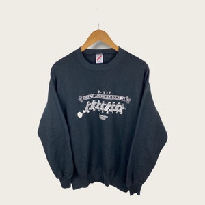 Könnte beinhalten: Schwarzer Pullover mit einem weißen Grafikdruck einer Gruppe von Menschen in Gefängnisuniformen mit dem Text "THE GREAT AMERICAN LOCKOUT" darüber.