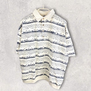 May include: A white short-sleeved polo shirt with a blue and white geometric pattern. The shirt has a button-up collar and a button placket.