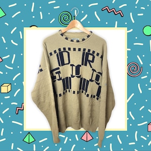 May include: A tan knitted jumper with a black and blue graphic design that reads "DIRT" on the front.
