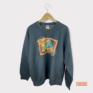 May include: A dark grey sweatshirt with a colourful graphic print of a winter scene and the text "Tis the Season".
