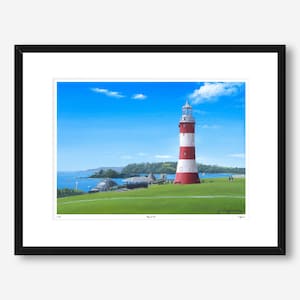 Puede incluir: Impresión enmarcada de un faro con rayas rojas y blancas, sobre un cielo azul con nubes. El faro está en una colina verde, con vistas al mar. La impresión está en un marco negro.