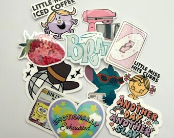May include: A collection of colorful stickers with various designs. Includes a strawberry, a pink stand mixer, a Stitch character, and text that reads "Little Miss Iced Coffee," "Emotionally Exhausted," and "Another Day Another Slay."