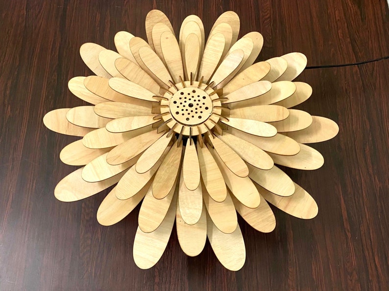 May include: A wooden flower-shaped ceiling light fixture with a circular center and multiple layers of petals.