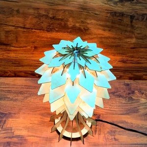 Peut inclure: Lampe de table en bois avec un design unique en couches ressemblant &agrave; une fleur ou un artichaut. La lampe est en bois clair et &eacute;met une lueur chaleureuse. La lampe mesure environ 30 cm de haut.