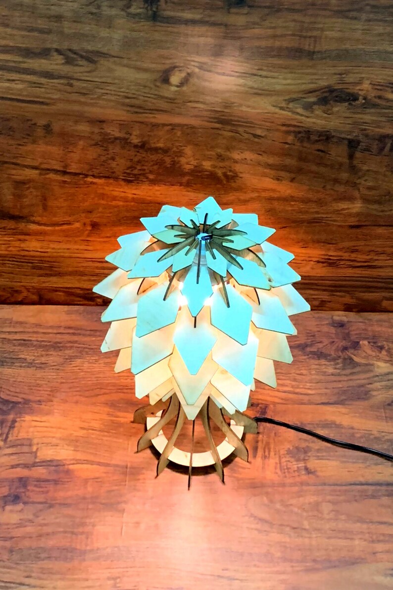 Peut inclure: Lampe de table en bois avec un design unique en couches ressemblant &agrave; une fleur ou un artichaut. La lampe est en bois clair et &eacute;met une lueur chaleureuse. La lampe mesure environ 30 cm de haut.