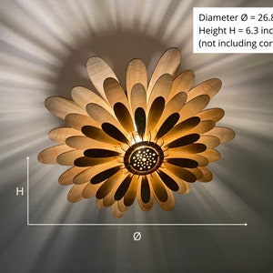 May include: A wooden ceiling light fixture shaped like a flower with 26.8 inches in diameter and 6.3 inches in height. The light fixture has a warm, golden glow and is made of many thin, wooden petals.