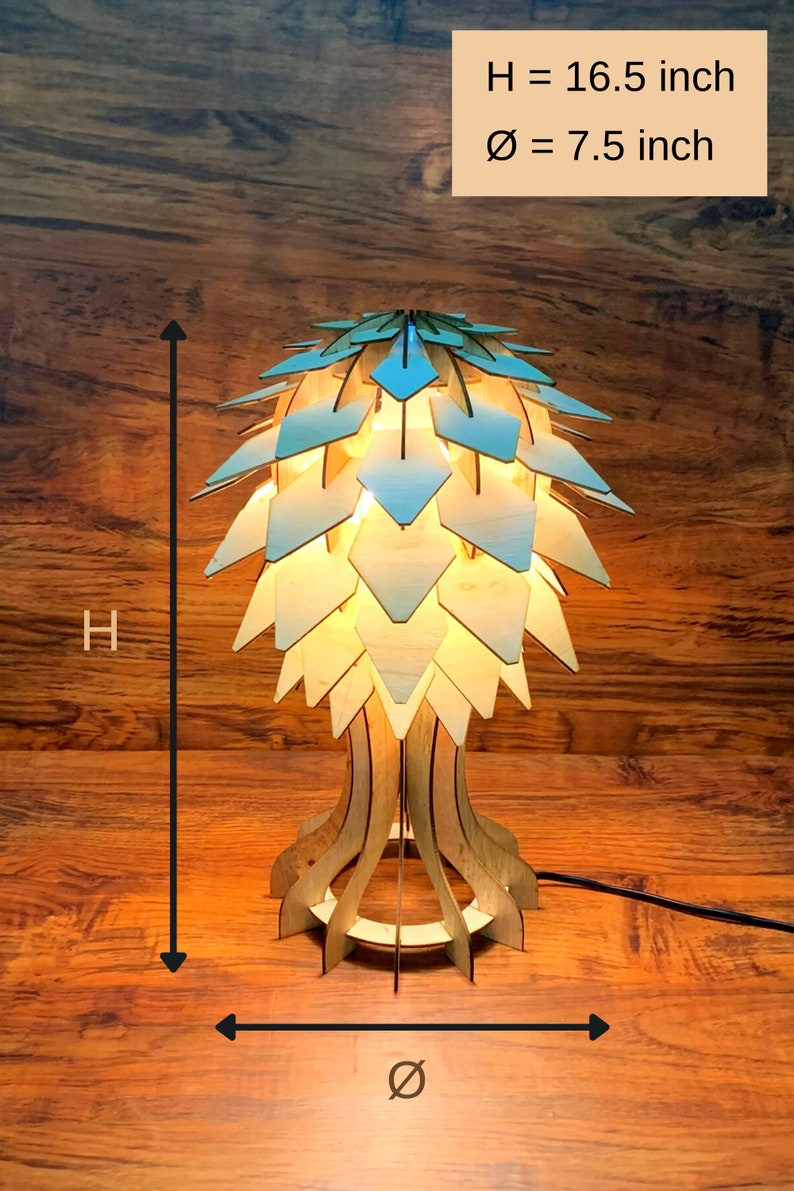 Op de afbeelding: Een houten tafellamp met een lichtblauw en wit geometrisch ontwerp. De lamp is 16,5 inch hoog en 7,5 inch in diameter.