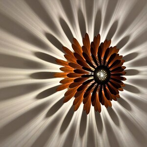 May include: A wooden ceiling light fixture shaped like a flower with brown petals and a central light source.