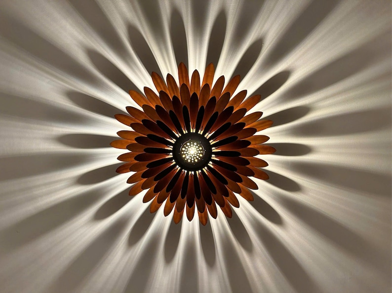 May include: A wooden ceiling light fixture shaped like a sunflower with brown petals and a central light source.