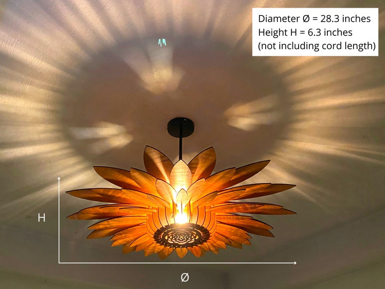 Puede incluir: Una l&aacute;mpara colgante de madera con forma de girasol con un di&aacute;metro de 72 cm y una altura de 16 cm. La luz cuelga del techo y proyecta un brillo c&aacute;lido.