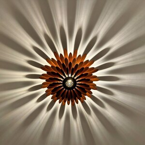 May include: A wooden ceiling light fixture shaped like a flower with brown petals and a central light source.