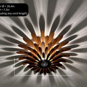 May include: A wooden ceiling light fixture shaped like a flower with brown and light brown petals. The light fixture is 26.4 inches in diameter and 7.3 inches tall.  The light fixture is mounted on a white ceiling.