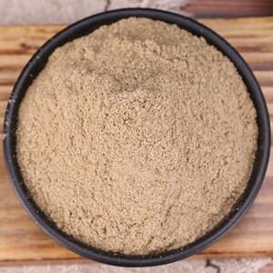 May include: A close-up view of a bowl filled with a light brown powder. The powder is finely ground and has a uniform texture.