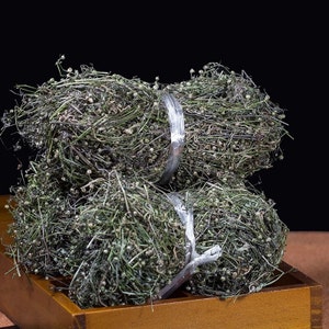 Peut inclure: Trois bottes d'herbes vertes séchées liées avec des bandes de plastique transparentes. Les herbes sont disposées dans une boîte en bois.