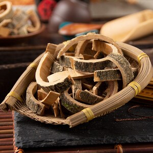 May include: A close-up of a woven basket filled with dried, curled pieces of bark. The bark is a light brown colour with a darker brown outer layer. The basket is made of natural woven material and has a yellow trim.