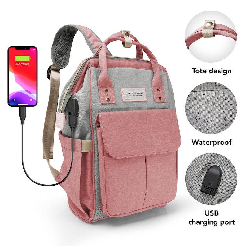 May include: A pink and gray diaper bag backpack with a tote design, a waterproof exterior, and a USB charging port. The bag has a Duncan Cooper logo on the front.