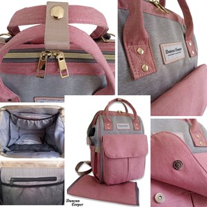 May include: A pink and gray diaper bag with a changing mat. The bag has a large main compartment, a front pocket, and two side pockets. The bag also has a zippered pocket on the front and a mesh pocket on the side. The bag has a handle on the top and adjustable straps. The bag is made of canvas and has a Duncan Cooper logo on the front.