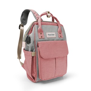 May include: A pink and gray diaper bag backpack with a front pocket and the text "Duncan Cooper" on the front.