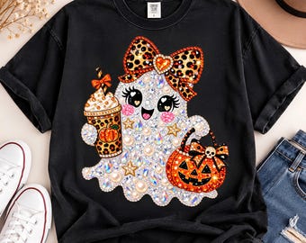 Może przedstawiać: Czarny t-shirt z grafiką białego ducha ozdobionego opalizującymi klejnotami i perłami. Duch ma kokardę w panterkę, trzyma kubek do kawy w panterkę z dynią i niesie wiaderko w kształcie dyni z kokardą z czaszką.