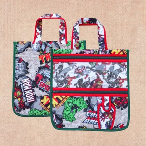 May include: Two green and red fabric bags with superhero character designs. The bags have zippered pockets and clear plastic windows. The bags have handles and are made of quilted fabric.