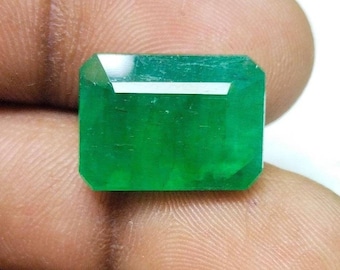 May include: A vibrant green emerald gemstone cut in an emerald shape.