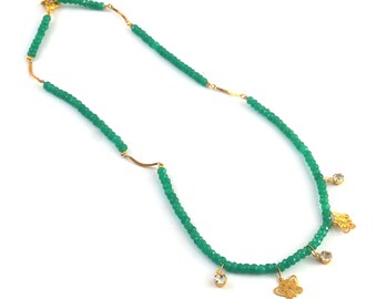May include: A green beaded necklace with gold accents and butterfly charms. The necklace has clear crystal accents.