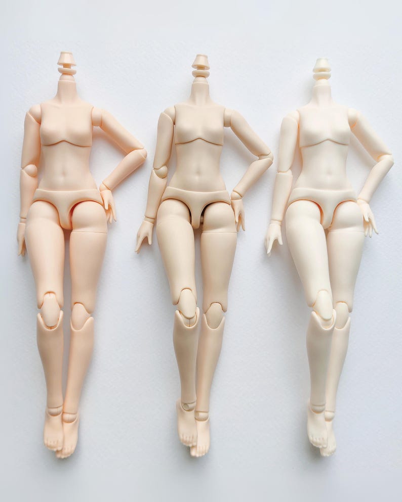 May include: Three nude-colored articulated doll bodies with no heads. The dolls are posed with their legs crossed and their arms bent at the elbows. The dolls are all the same size and have the same body type.