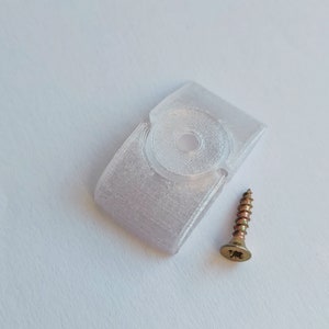 以下が含まれることがあります： 中央に丸い穴があり、金色のネジが付いた白いプラスチック製の壁掛け