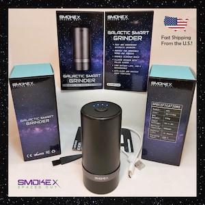 以下が含まれることがあります： 青く光るトップが付いた黒色のGalactic Smart Grinder。製品は、テキスト「Galactic Smart Grinder」と仕様を含むパッケージとともに表示されます。グラインダーは円筒形で、USB-C充電ケーブルが付属しています。