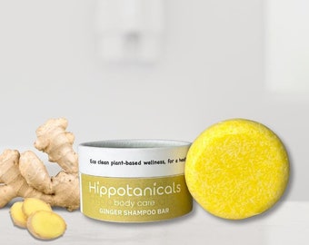 May include: A yellow ginger shampoo bar in a white container with the text "Hippotanicals body care GINGER SHAMPOO BAR" on the container. A piece of ginger root is next to the container.
