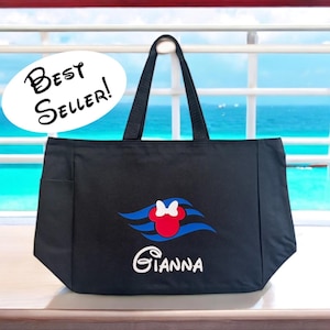 May include: Black tote bag with a Minnie Mouse design in red, white, and blue, with the name "Gianna" in white script. The bag has a side pocket and black handles. The text "Best Seller!" is in a white oval.