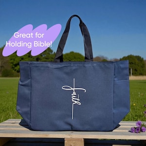 May include: Navy blue tote bag with black handles and a white "Faith" script design. The bag has side pockets and is displayed on a wooden pallet. The text "Great for Holding Bible!" is in a purple bubble.