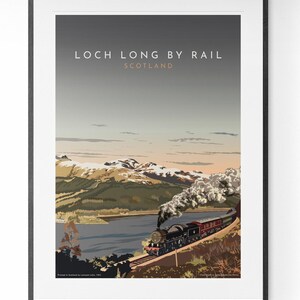 May include: Framed art print featuring a vintage travel poster for Loch Long by Rail in Scotland. The artwork depicts a steam train traveling along a track with a lake and mountains in the background. The sky is a gradient of gray and orange.