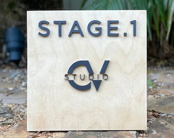 May include: A wooden sign with the text "STAGE.1" and the logo "CV STUDIO" in black lettering.